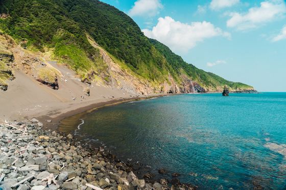 Black-sand beach and turquoise sea on the Izu Oshima coast